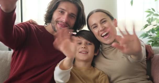 Lykkelig familie vinker hænder ser på kameraet – Stock-video