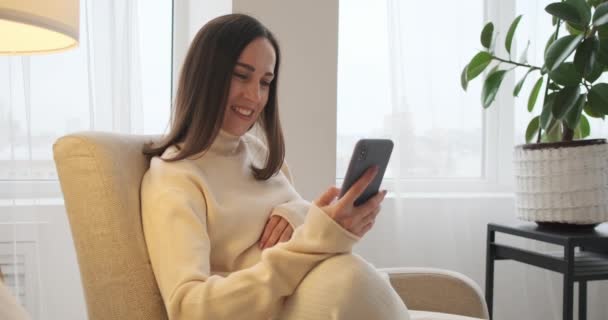 Gravid kvinna bläddrar på mobiltelefon hemma — Stockvideo