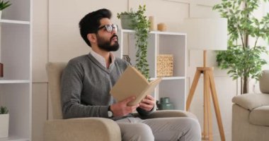 Koltukta oturan ve kitap okuyan bir adam.