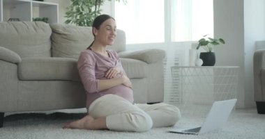 Hamile kadın evde dizüstü bilgisayarla video sohbeti yapıyor.