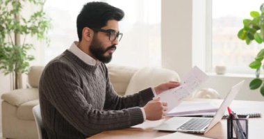 İşadamı dizüstü bilgisayarda video konferansı yaparken belgeyi okuyor