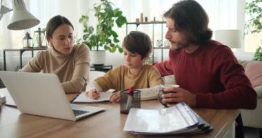 Ebeveynler oğullarına ödevlerinde yardım ediyor.