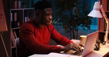 Genç Afrikalı Amerikalı işadamı gece yarısı dizüstü bilgisayar kullanıyor.