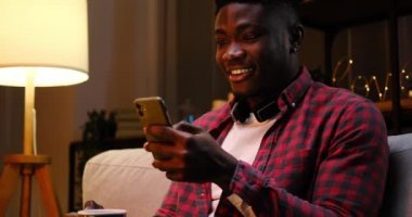Şaşırmış Afrikalı Amerikalı adam gece geç saatlerde cep telefonu kullanıyor.