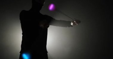 Kar maskeli genç adamın silueti Poi 'nin el aksesuarlarını döndürüyor.