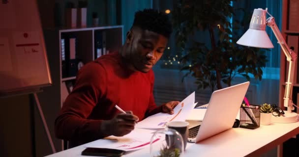 African American businessman doing paperwork late night — Stock Video