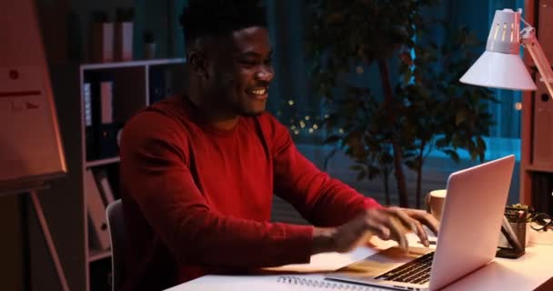 Felice uomo afroamericano chiusura computer portatile e alzarsi a tarda notte — Video Stock