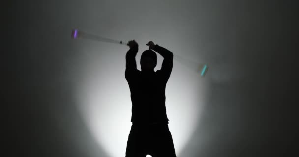 Silhouette of young man in mask spinning led poi hand props — ストック動画