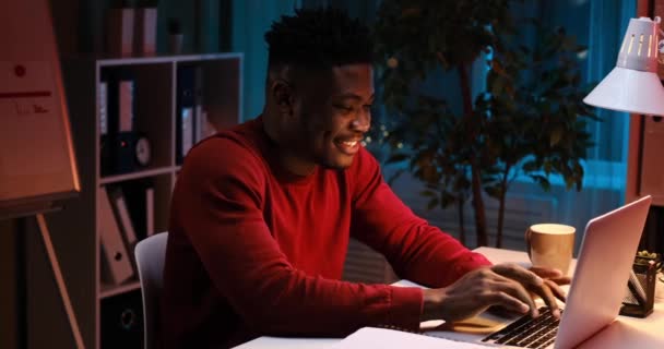 Felice uomo d'affari afroamericano digitando utilizzando computer portatile a tarda notte — Video Stock