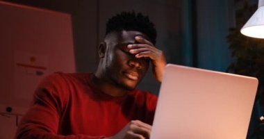 Yorgun Afrikalı Amerikalı işadamı gece geç saatlerde evrak işleriyle uğraşırken esniyor.