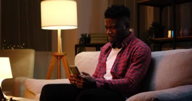 Afro-Amerikalı adam cep telefonu kullanıyor ve kahve içiyor.