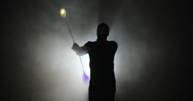 Kar maskeli genç adamın silueti Poi 'nin el aksesuarlarını döndürüyor.