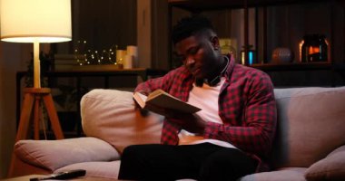 Afrika kökenli Amerikalı bir adam gece kitap okuyor.