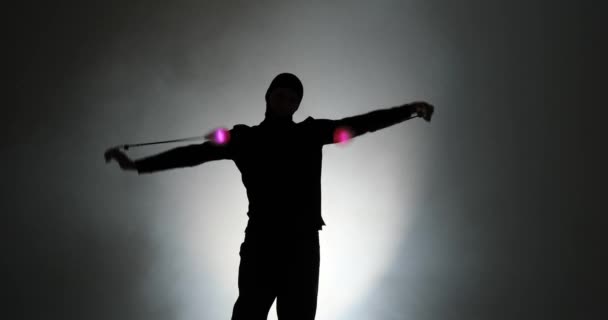 Silhouette of young man in balaclava mask spinning led poi hand props — ストック動画