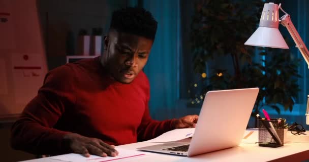 Serious African American businessman using laptop for video conference late night — Stock Video