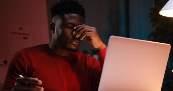 Cansado hombre de negocios afroamericano trabajando en portátil hasta tarde por la noche — Vídeos de Stock