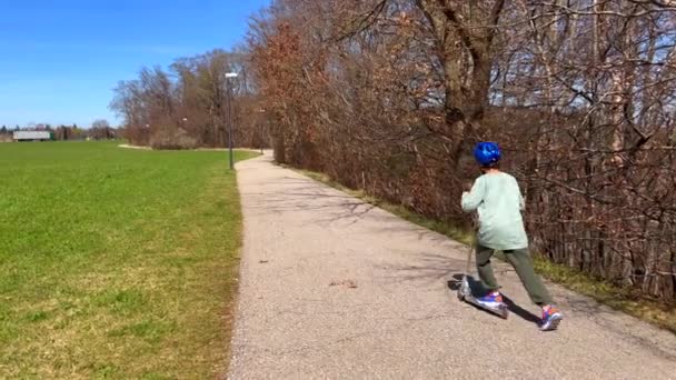 Niño montando un scooter en el parque — Vídeo de stock