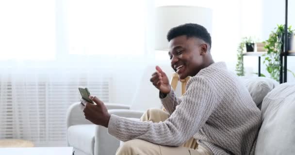 Χαρούμενος άνθρωπος βίντεο κουβεντιάζοντας χρησιμοποιώντας το κινητό τηλέφωνο κάθεται στον καναπέ — Αρχείο Βίντεο