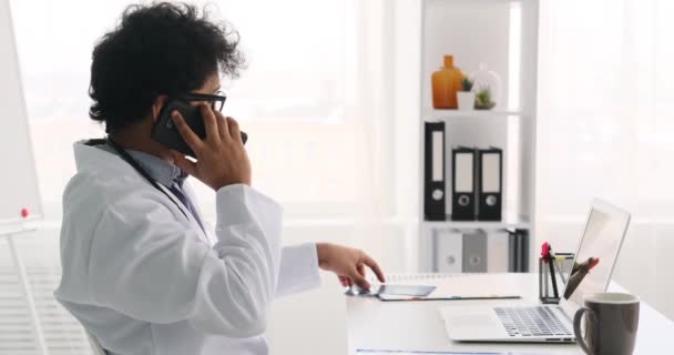 Xrayレポートを調べながら携帯電話で話す医師 — ストック動画