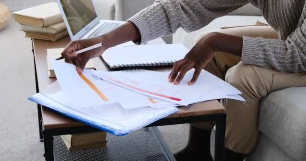 소파에 앉아서 서류 상으로 글을 쓰는 사람 — 비디오