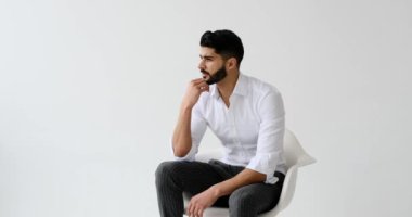 Beyaz arka planda oturan yakışıklı adam