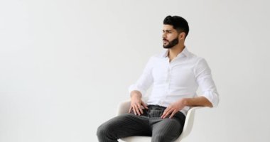 Beyaz arka planda oturan yakışıklı adam