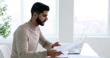 İşadamı laptopta çalışıyor ve ofiste notlar yazıyor.