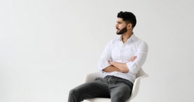 Beyaz arka planda oturan yakışıklı adam.