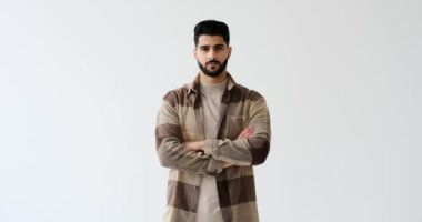 Kolları beyaz arka planda çapraz duran kendinden emin bir adam.