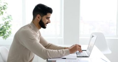 Ofiste dizüstü bilgisayar kullanan gülümseyen adam