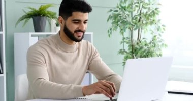 Ofiste dizüstü bilgisayarda yazan mutlu adam.