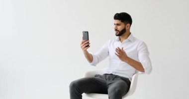 Sinirli bir adam cep telefonuyla görüntülü konuşuyor. 