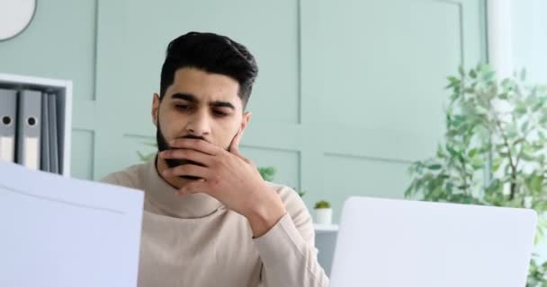 Geschäftsmann analysiert Dokument und nutzt Laptop im Büro — Stockvideo