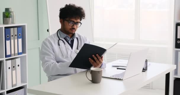 Dokter membaca laporan dan menggunakan laptop di kantor — Stok Video