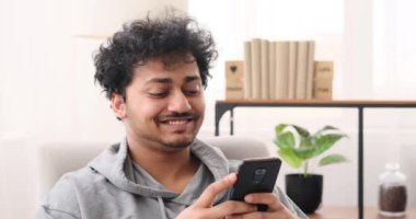 Genç adam koltukta cep telefonu kullanıyor.