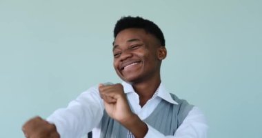 Mavi arka planda gülümseyen ve dans eden Afrikalı Amerikalı adam.