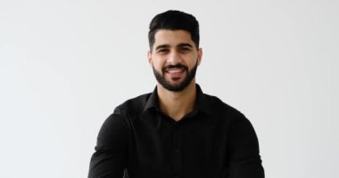 Kollarını kavuşturup beyaz arka planda gülümseyen mutlu genç adam.