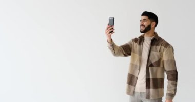 Mutlu genç adam beyaz arka planda cep telefonuyla görüntülü sohbet.