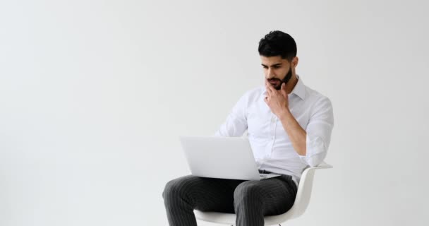 Bonito Homem Digitando Laptop Enquanto Sentado Contra Fundo Branco — Vídeo de Stock