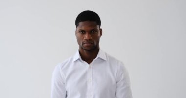 Beyaz arka planda kollarını kavuşturmuş ciddi bir Afrikalı Amerikalı iş adamı.