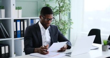 Sinirli Afrikalı Amerikalı iş adamı ofisteki dizüstü bilgisayarla online konferans görüşmesinde tartışıyor.