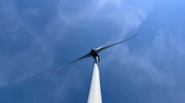 Wind turbine rotating powered by wind against blue sky