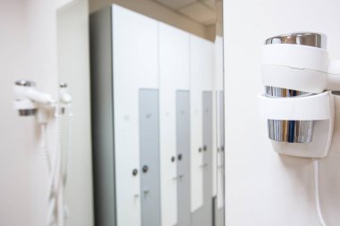 Ahşap dolapları, bankları ve özel ekipmanları olan beyaz bir soyunma odası olan geniş çerçeve.