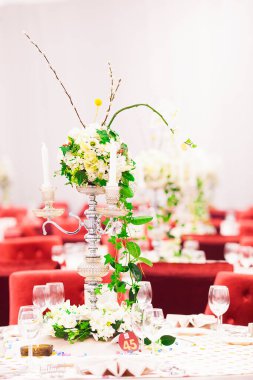 Lüks bir düğün resepsiyonunda masa. Masada güzel çiçekler var. Servis tabakları, cam bardaklar, garsonlar. Sağlık ve yaşam tarzı