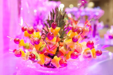 Çikolata, şekerli masa, nefis çörekler ışıklı bir masada cam tabakta yatıyor.