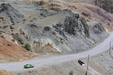 view of the mountainous area in spring, bare stone, the car is standing on the road