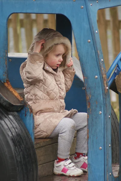 Młoda dziewczyna gra w niebieski ciągnik — Zdjęcie stockowe
