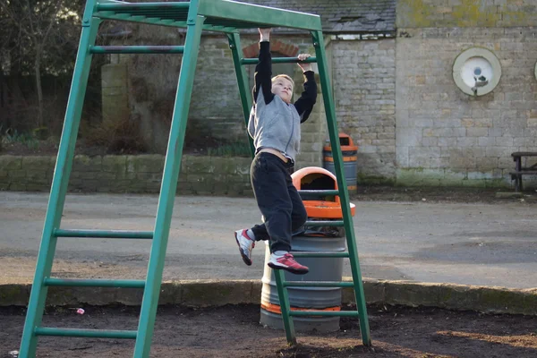 Jonge jongen klimmen op monkey bars — Stockfoto