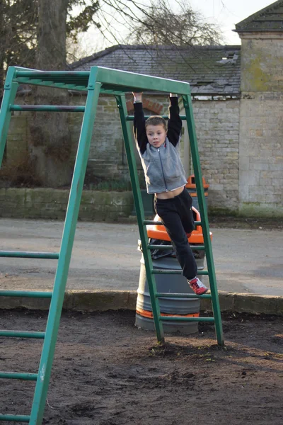 Jonge jongen klimmen op monkey bars — Stockfoto