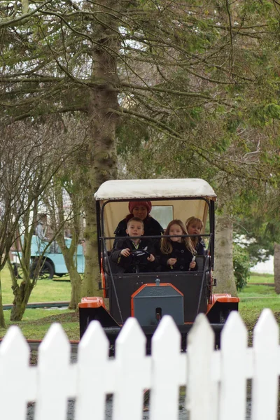 Jonge gezin op een oranje auto fairgound rit — Stockfoto